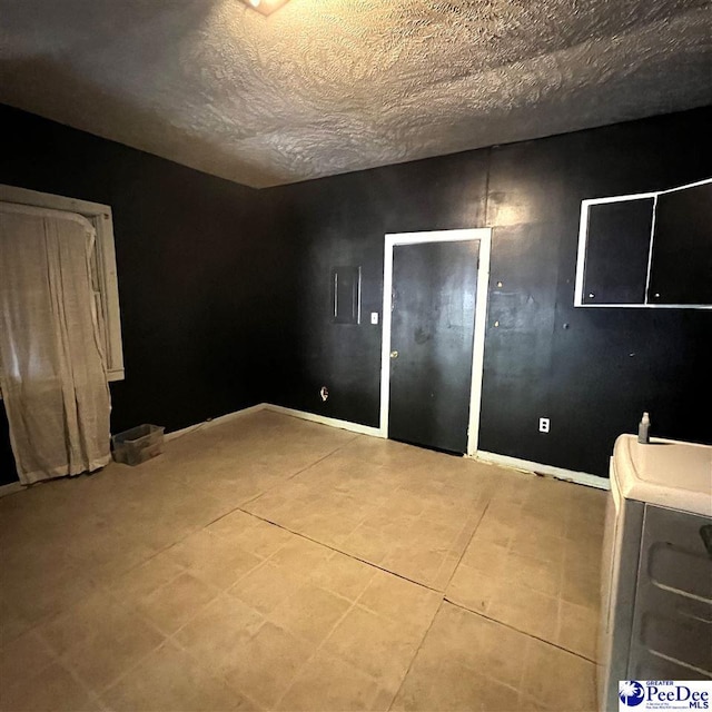 empty room featuring washer / dryer, light tile patterned floors, and a textured ceiling