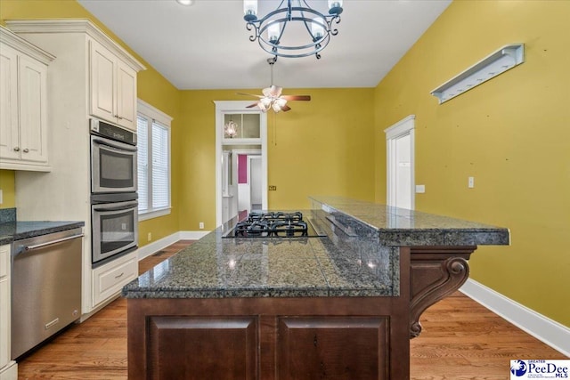 302 Cashua St, Darlington, SC 29532 - kitchen featuring stainless steel appliances, a center island, wood finished floors, baseboards, and dark countertops