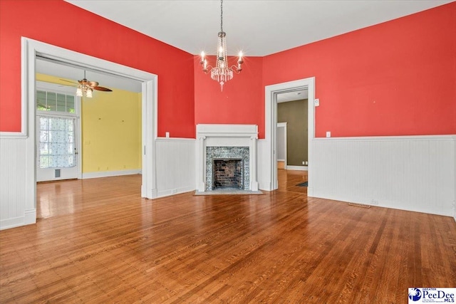 302 Cashua St, Darlington, SC 29532 - unfurnished living room with wainscoting, wood finished floors, a chandelier, a fireplace with flush hearth, and ceiling fan