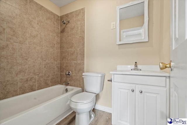 full bathroom with hardwood / wood-style flooring, tiled shower / bath, vanity, and toilet