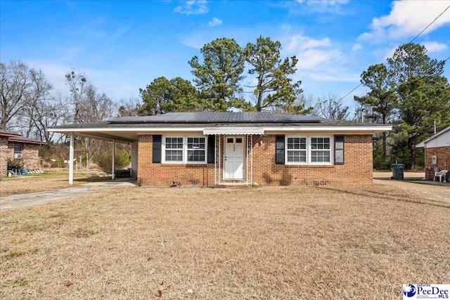 single story home featuring a carport, a front lawn, and solar panels