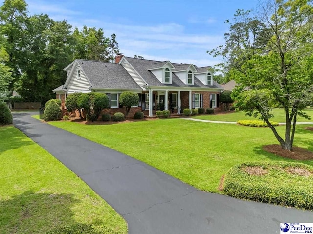 439 Whitman Ave, Florence, SC 29501 - new england style home with covered porch, brick siding, a front lawn, and roof with shingles