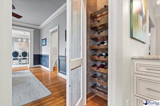 439 Whitman Ave, Florence, SC 29501 - hallway featuring ornamental molding, light wood finished floors, a wainscoted wall, and a chandelier