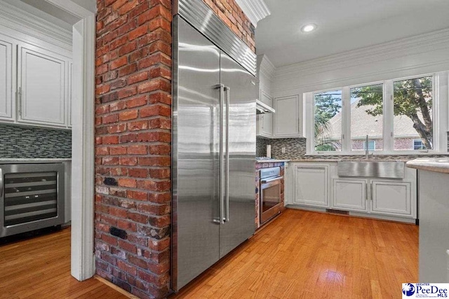 439 Whitman Ave, Florence, SC 29501 - kitchen featuring stainless steel appliances, wine cooler, light wood-type flooring, tasteful backsplash, and white cabinetry