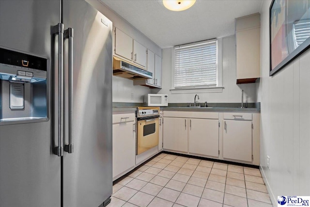 439 Whitman Ave, Florence, SC 29501 - kitchen featuring stainless steel appliances, under cabinet range hood, light tile patterned flooring, and dark countertops