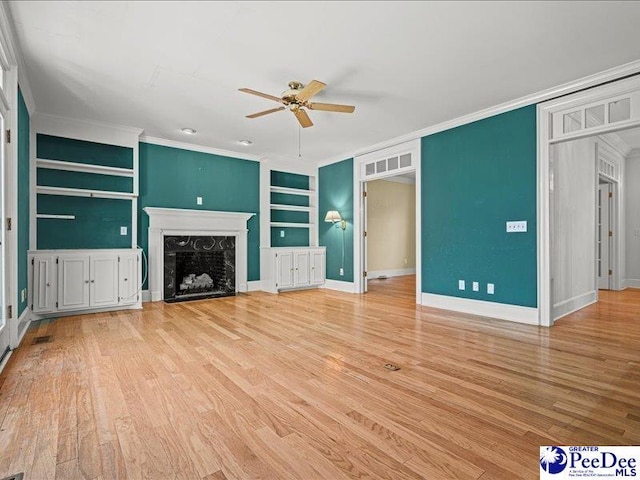 unfurnished living room featuring crown molding, a fireplace, built in shelves, and light hardwood / wood-style flooring