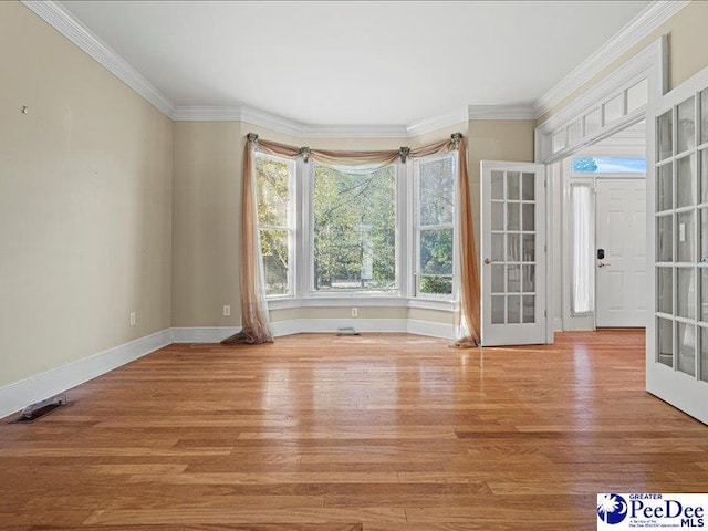 spare room featuring crown molding, light hardwood / wood-style floors, and french doors