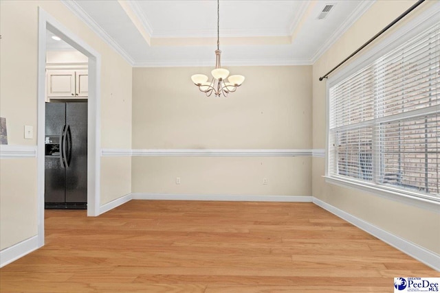 unfurnished dining area with plenty of natural light, light hardwood / wood-style floors, and a raised ceiling