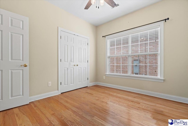 unfurnished bedroom featuring ceiling fan, a closet, and light wood-type flooring