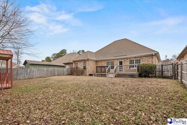 rear view of property featuring a wooden deck and a lawn