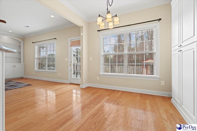 unfurnished dining area with crown molding, an inviting chandelier, and light hardwood / wood-style flooring