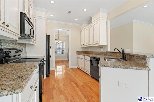 kitchen featuring sink, black appliances, kitchen peninsula, light stone countertops, and white cabinets