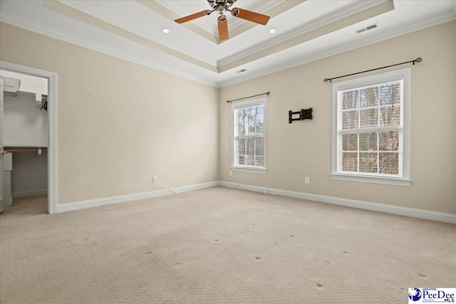 carpeted spare room featuring a raised ceiling, ornamental molding, and ceiling fan