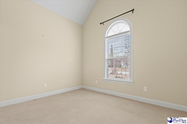 carpeted spare room with vaulted ceiling