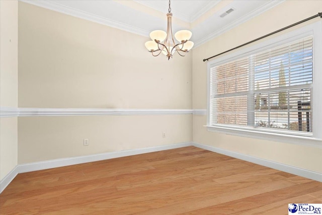 spare room featuring ornamental molding, a notable chandelier, light hardwood / wood-style floors, and a tray ceiling