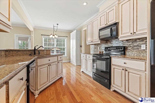 kitchen featuring sink, hanging light fixtures, ornamental molding, black appliances, and light stone countertops