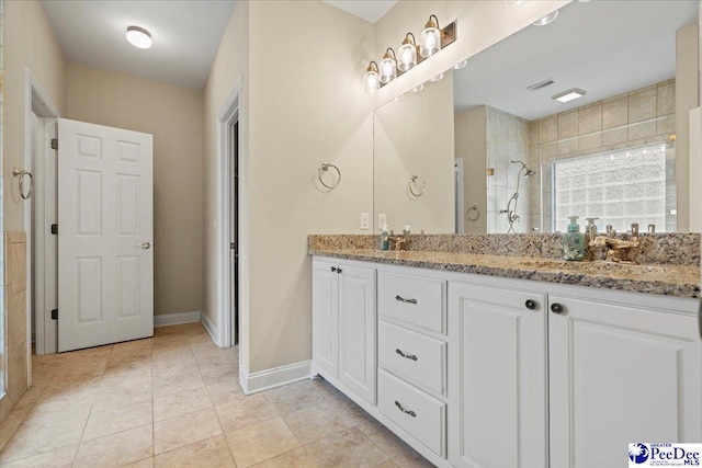 bathroom featuring a tile shower, vanity, and tile patterned floors