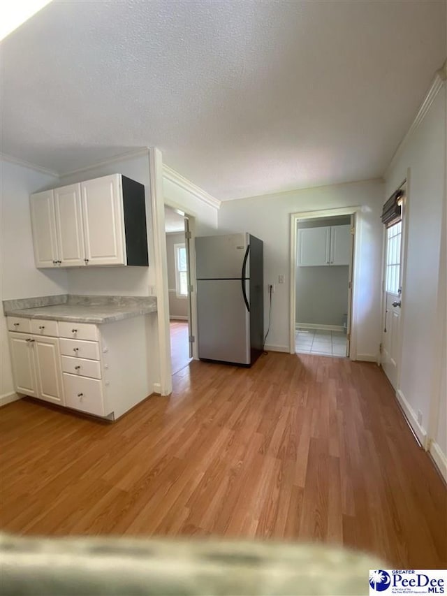 867 Congaree Dr, Florence, SC 29501 - kitchen featuring freestanding refrigerator, light countertops, light wood-style floors, white cabinets, and crown molding