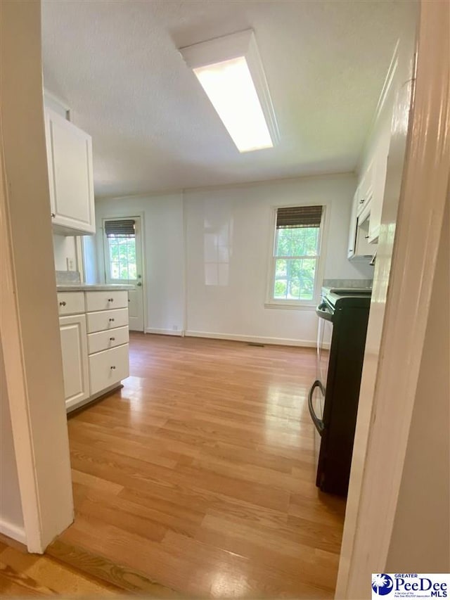 867 Congaree Dr, Florence, SC 29501 - kitchen with black electric range, white cabinets, light wood-style flooring, and plenty of natural light