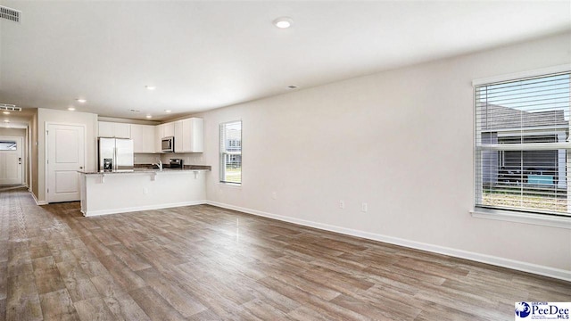 575 Strawberry Field Way, Galivants Ferry, SC 29544 - kitchen featuring fridge with ice dispenser, wood finished floors, white cabinetry, a breakfast bar, and a peninsula