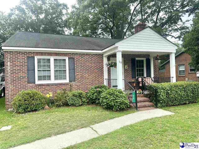 59 Lynn Ave, Cheraw, SC 29520 - view of front of property featuring brick siding, a front yard, a porch, and a chimney
