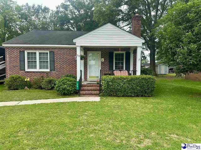 59 Lynn Ave, Cheraw, SC 29520 - view of front of property featuring a chimney, a front yard, covered porch, and brick siding