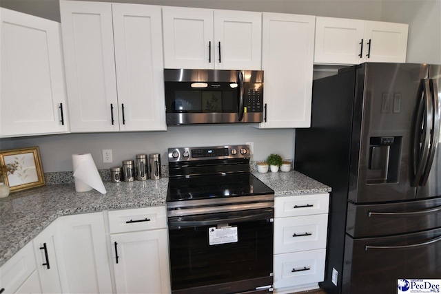 kitchen featuring white cabinetry, refrigerator with ice dispenser, light stone counters, and electric range