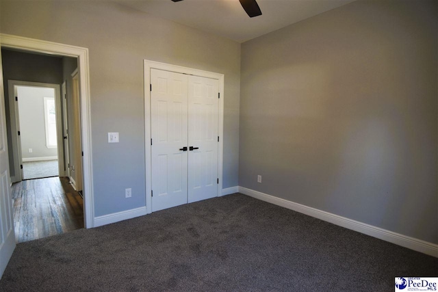 unfurnished bedroom with ceiling fan, dark carpet, and a closet