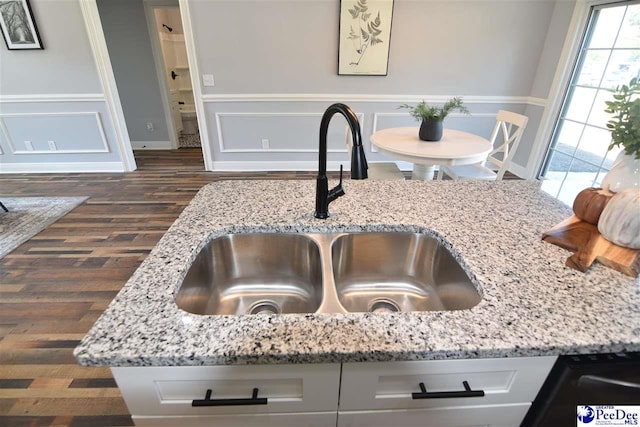 interior details with sink, light stone countertops, and dark hardwood / wood-style floors