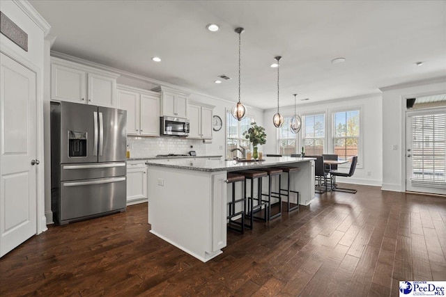 207 Compass Trl, Blythewood, SC 29016 - kitchen featuring dark wood-style flooring, a breakfast bar, an island with sink, decorative backsplash, and appliances with stainless steel finishes