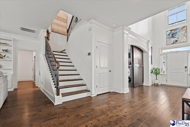 207 Compass Trl, Blythewood, SC 29016 - entryway with dark wood-style floors, crown molding, stairs, visible vents, and arched walkways