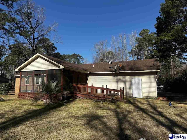 back of property with a sunroom, a deck, and a lawn