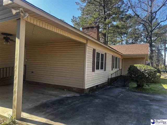 view of side of property with a carport, crawl space, and a chimney