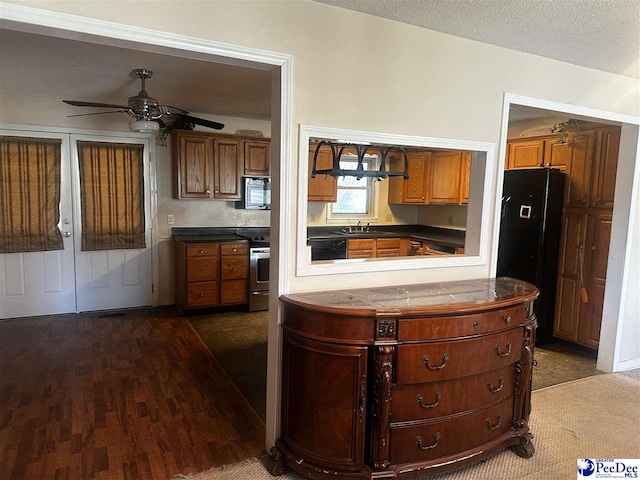 kitchen featuring dark wood-style flooring, brown cabinets, appliances with stainless steel finishes, a sink, and a textured ceiling