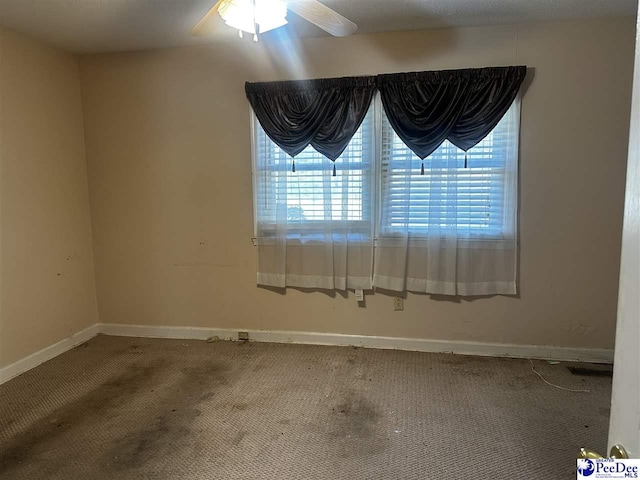 carpeted empty room featuring ceiling fan and baseboards