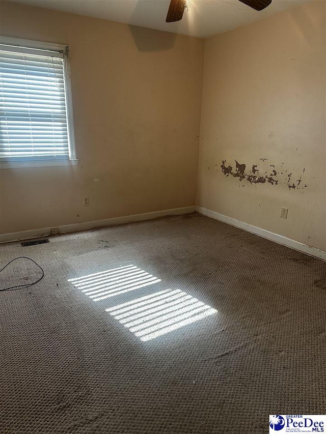 empty room with carpet, visible vents, ceiling fan, and baseboards