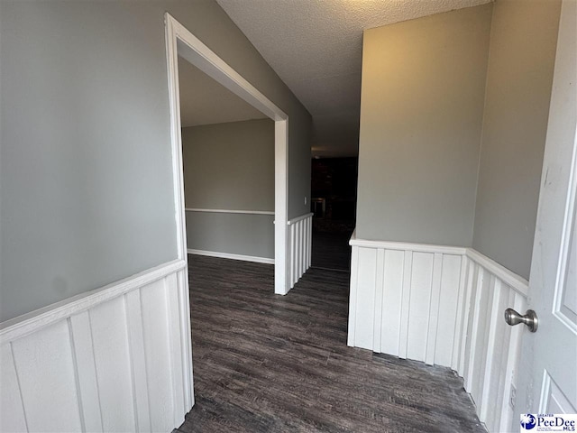 hallway featuring dark wood-type flooring and a textured ceiling
