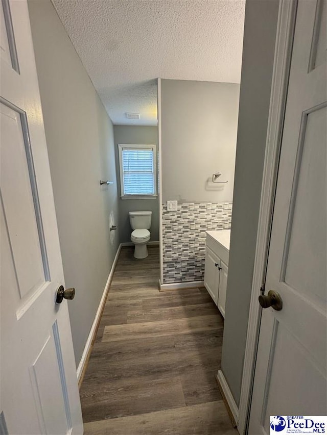 bathroom featuring hardwood / wood-style flooring, vanity, toilet, and a textured ceiling