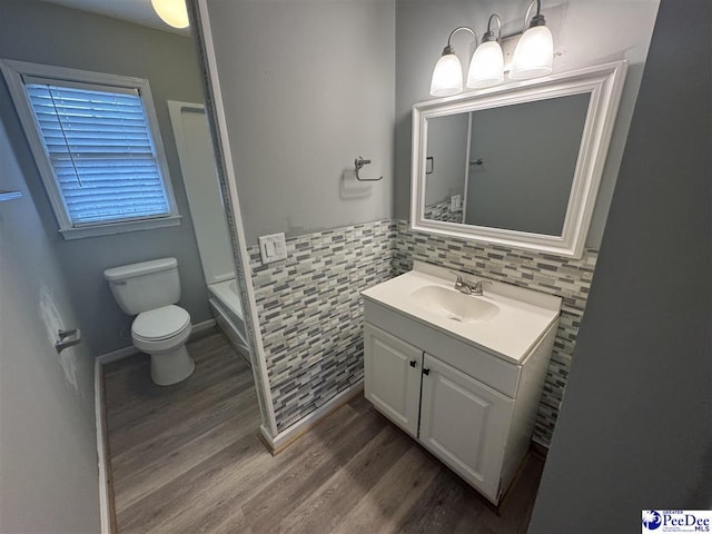 bathroom featuring vanity, toilet, wood-type flooring, and tile walls