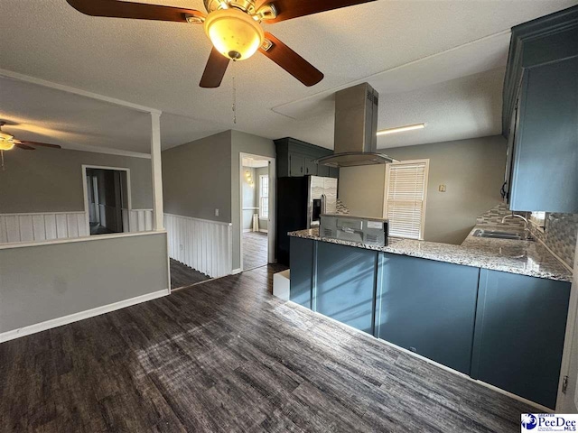 kitchen featuring sink, light stone counters, island range hood, dark hardwood / wood-style floors, and kitchen peninsula