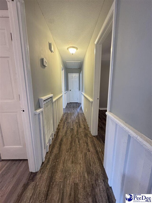 corridor with dark wood-type flooring and a textured ceiling