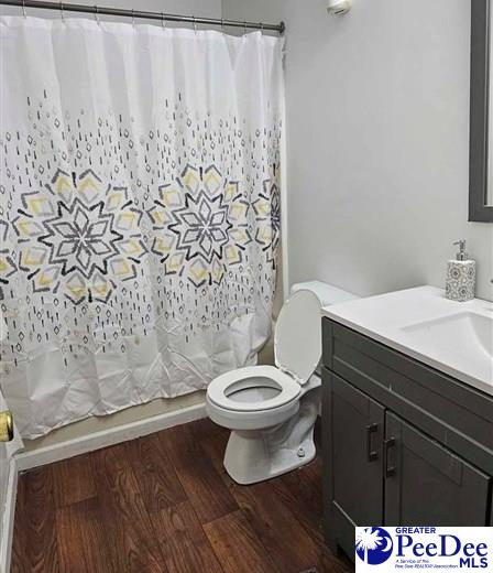 full bathroom featuring vanity, hardwood / wood-style flooring, toilet, and shower / tub combo with curtain