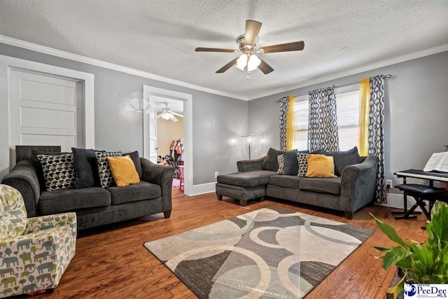 living room with ceiling fan, wood-type flooring, ornamental molding, and a textured ceiling