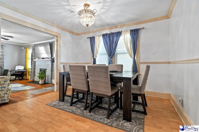 427 Marlboro Ave, Hartsville, SC 29550 - dining room featuring wood-type flooring, a chandelier, a textured ceiling, ornamental molding, and a fireplace