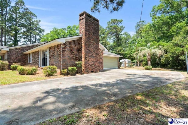 821 W Shirley Rd, Pamplico, SC 29583 - view of home's exterior featuring brick siding, concrete driveway, and a chimney