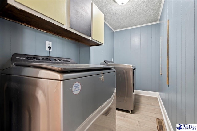 821 W Shirley Rd, Pamplico, SC 29583 - laundry area featuring cabinet space, independent washer and dryer, light wood-style floors, baseboards, and a textured ceiling