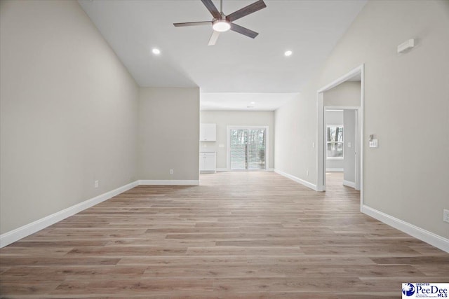 unfurnished living room with ceiling fan, vaulted ceiling, and light hardwood / wood-style floors