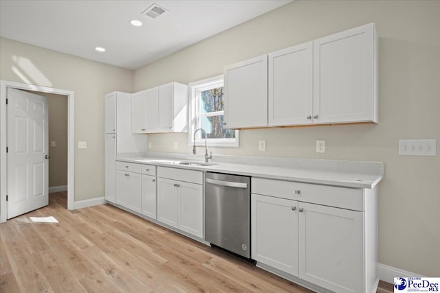 kitchen with sink, stainless steel dishwasher, white cabinets, and light hardwood / wood-style flooring