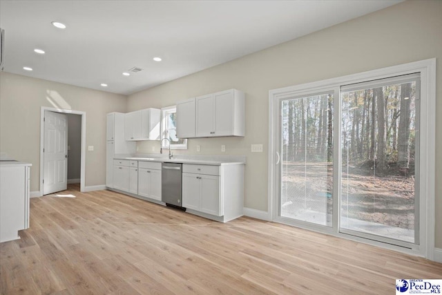 kitchen with stainless steel dishwasher, white cabinets, and light hardwood / wood-style flooring