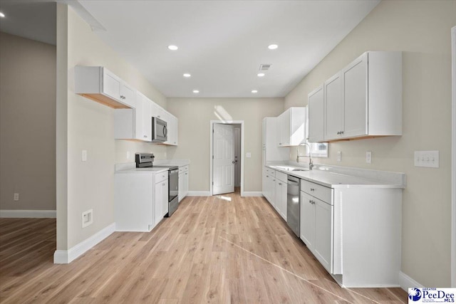 kitchen featuring sink, stainless steel appliances, light hardwood / wood-style floors, and white cabinets